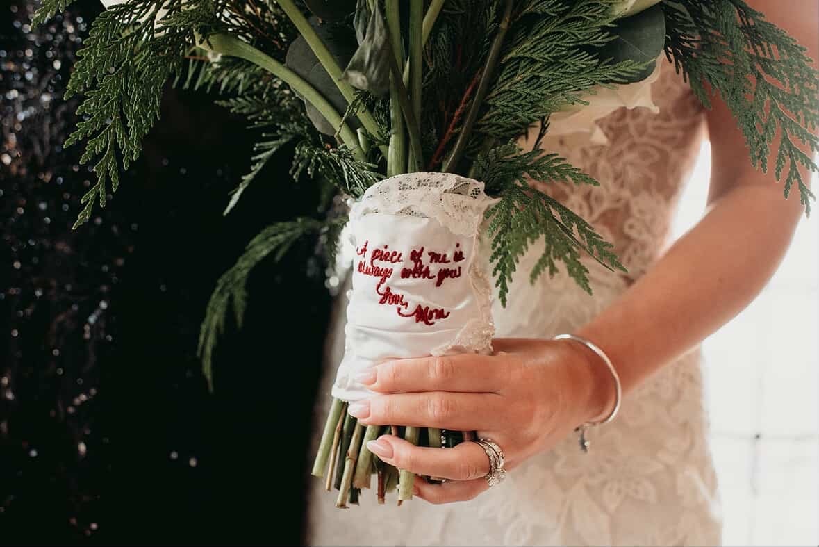 Embroidered handwriting on fabric from wedding dress wrapped around bride's bouquet. Thread is burgundy.