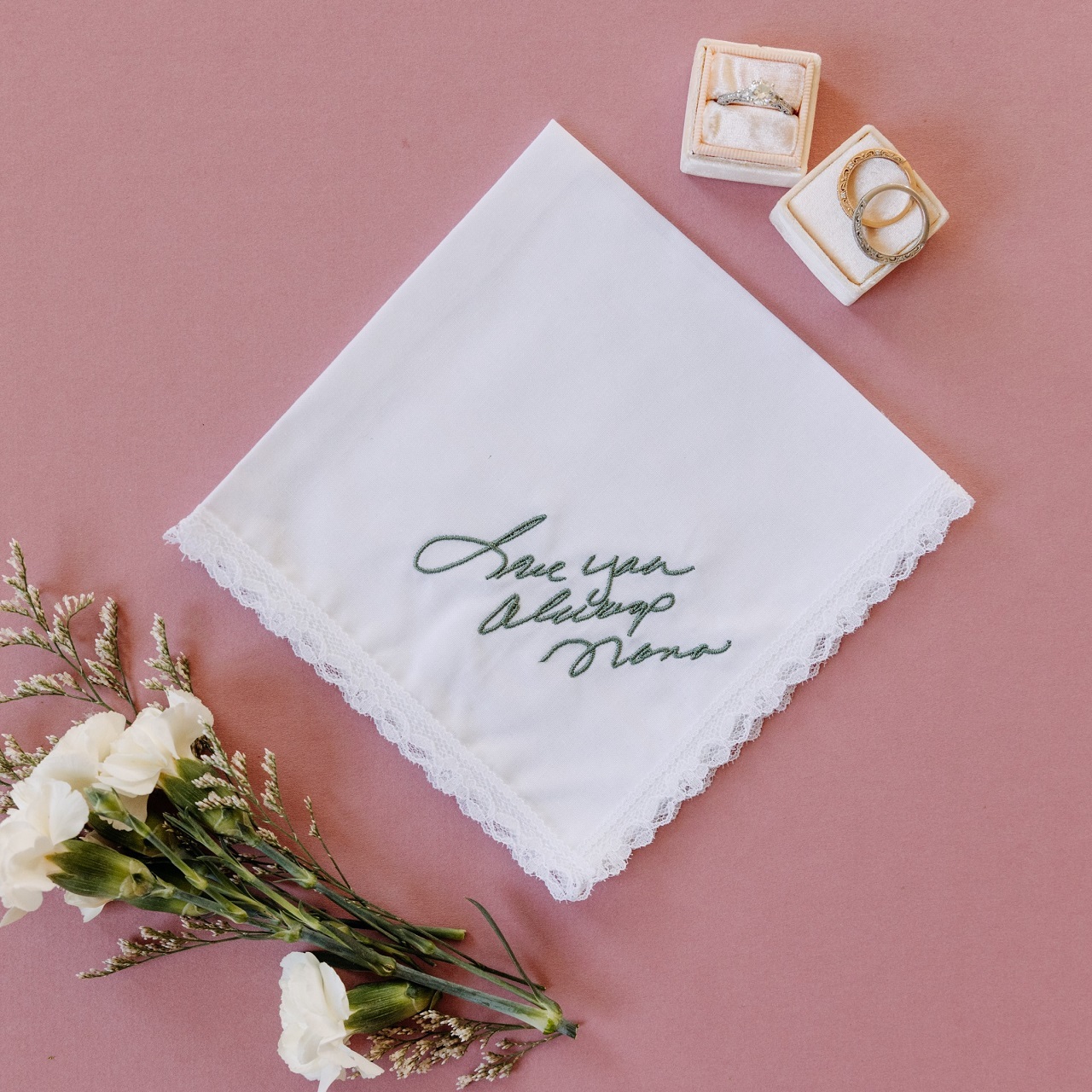 White lace handkerchief with handwriting embroidered on it from a grandparent in sage thread.